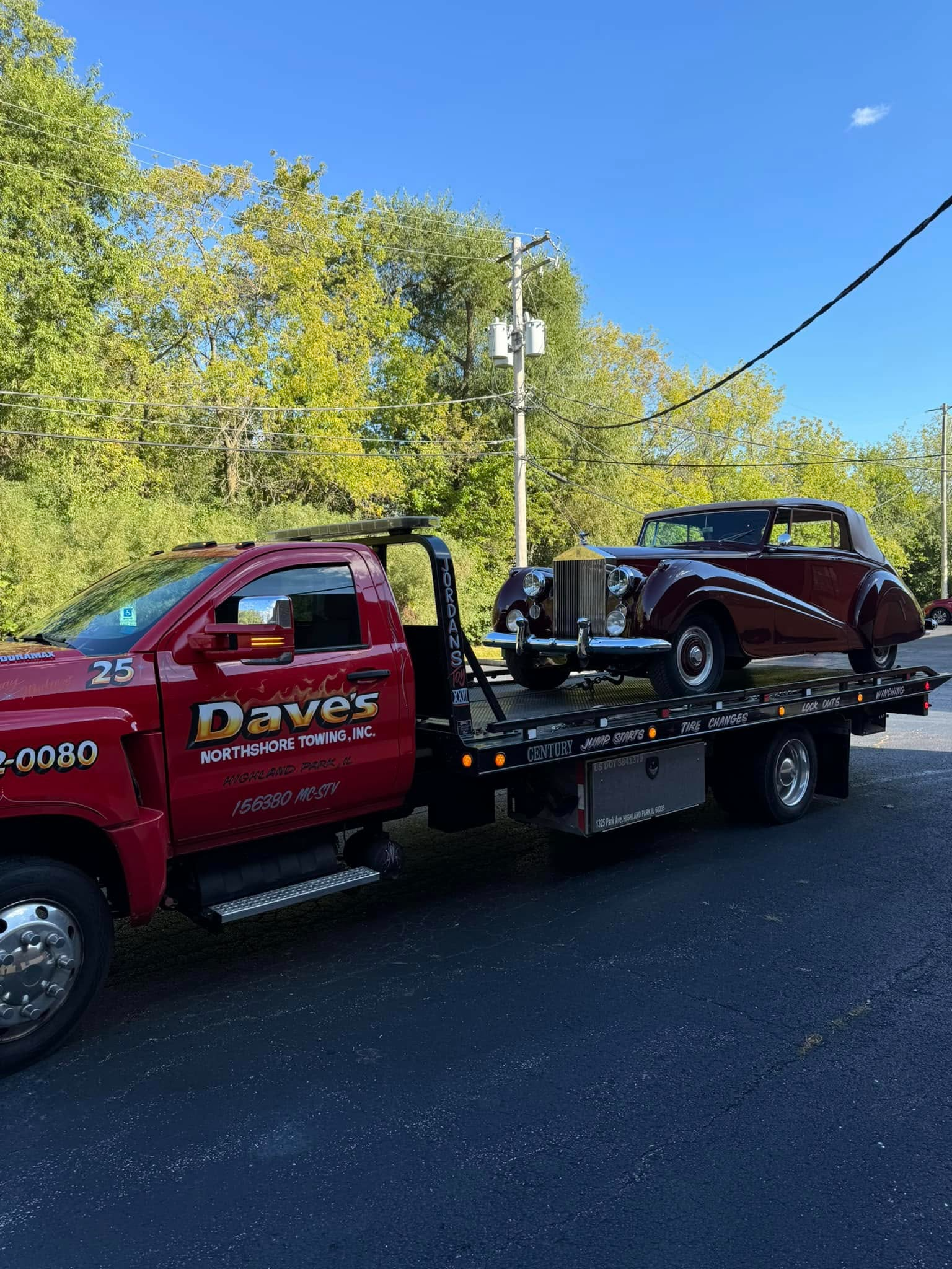 A red tow truck is towing a red car on a flatbed trailer.