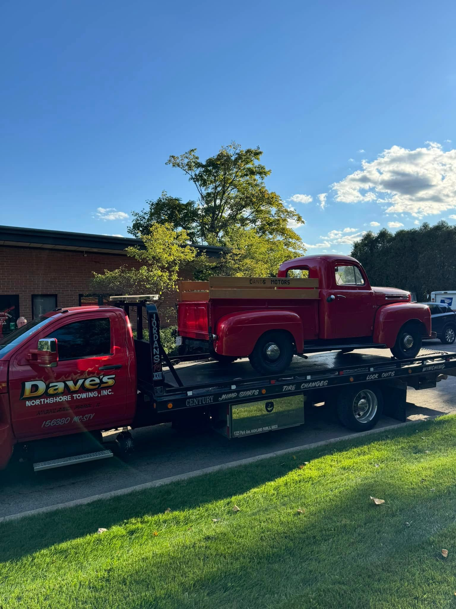 A red truck is being towed by a tow truck.