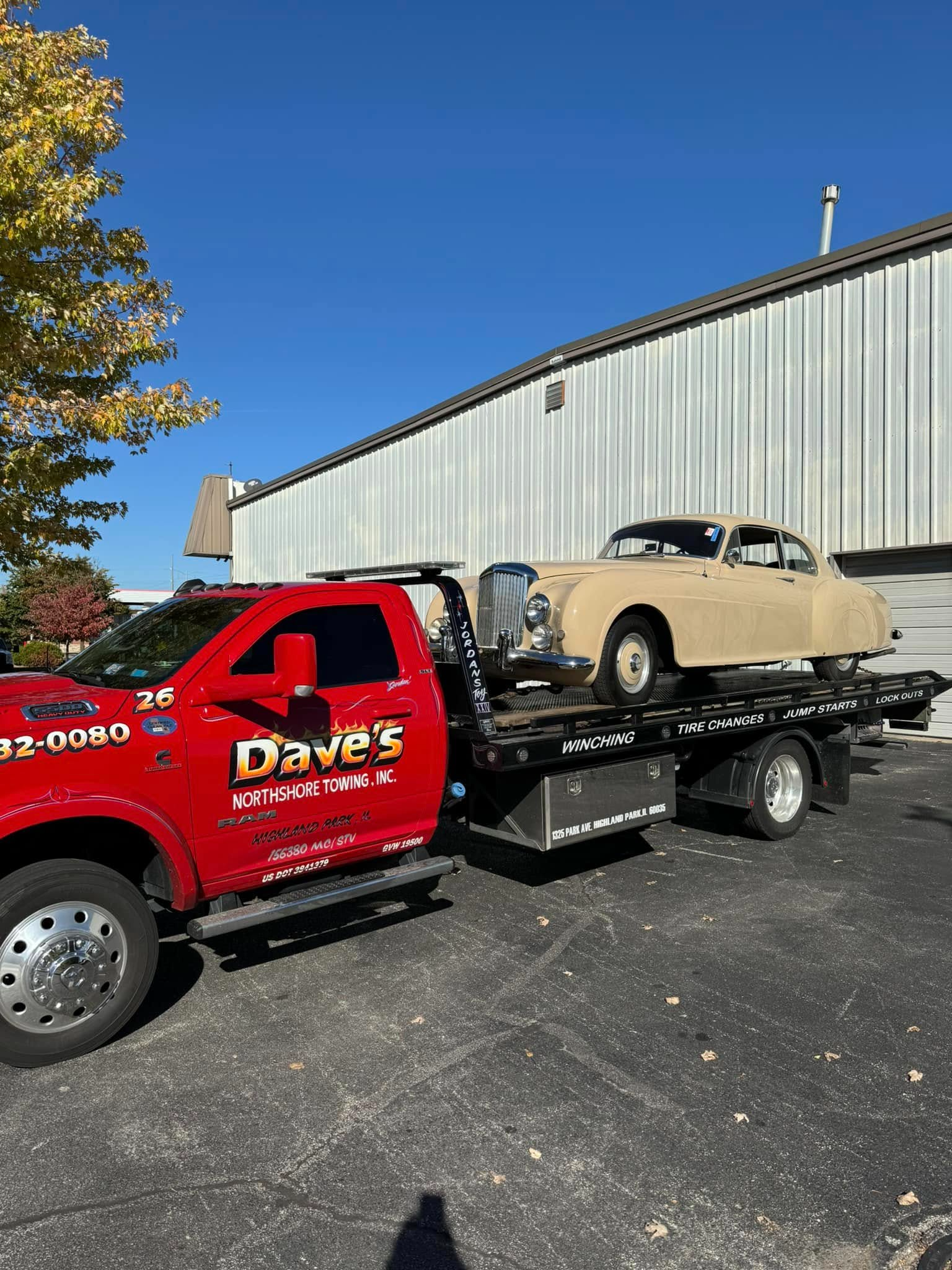 A tow truck is carrying a car on the back of it.