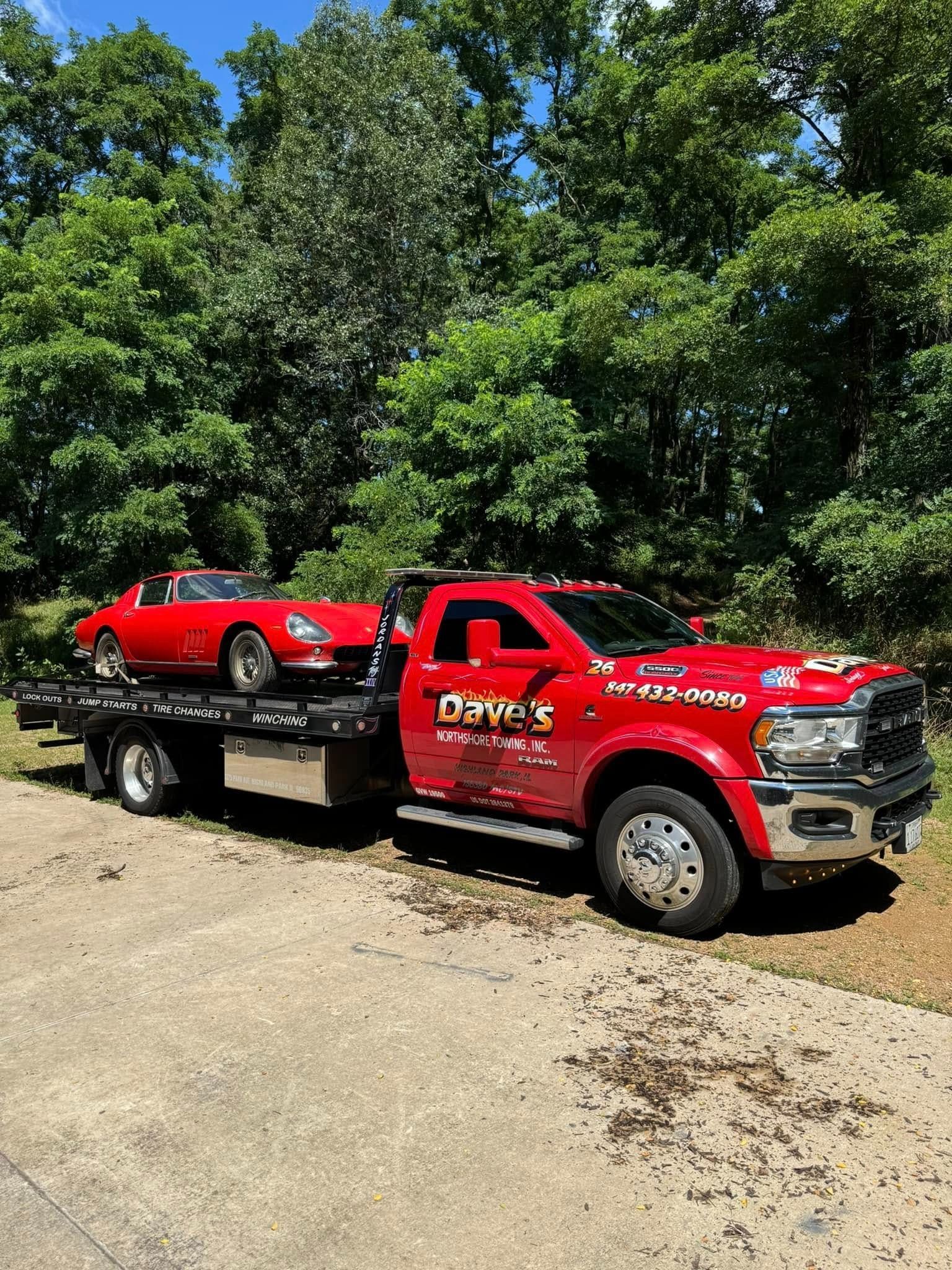 A red tow truck is carrying a red sports car.