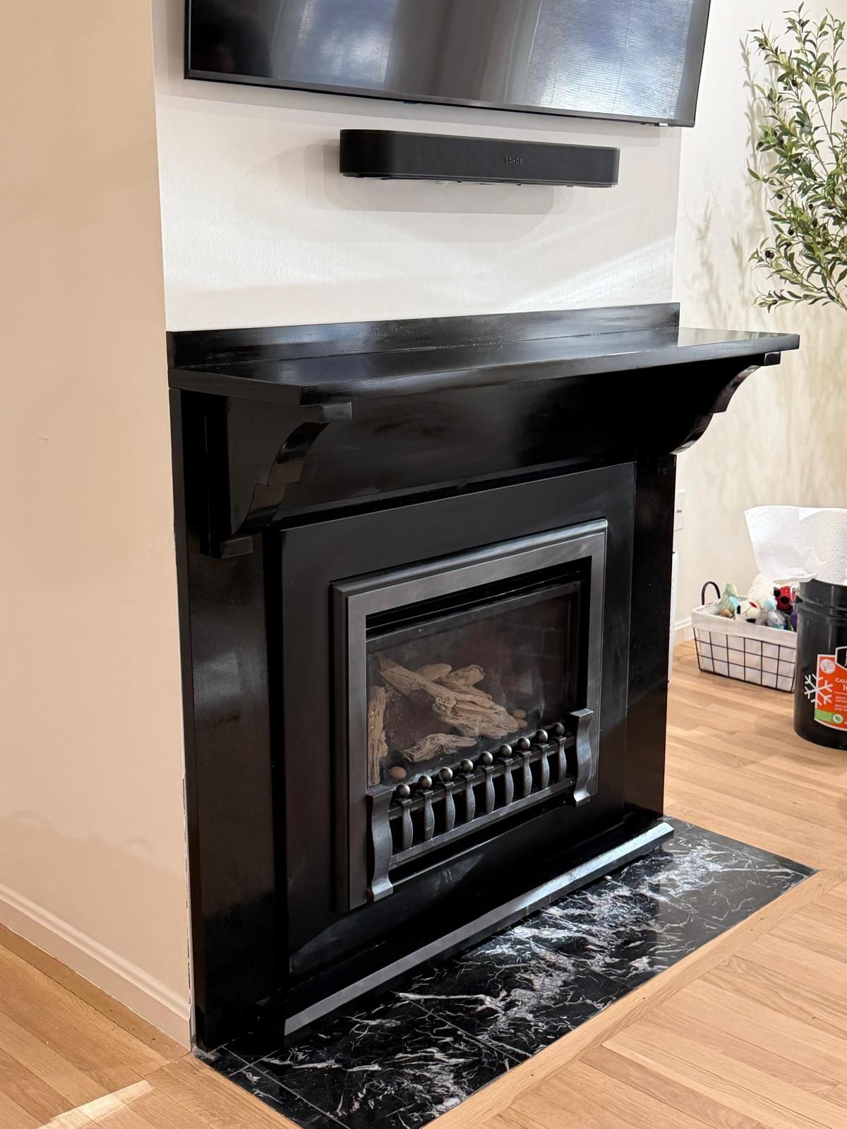 Black fireplace with a mounted television and soundbar. The surround is black with a marble hearth.