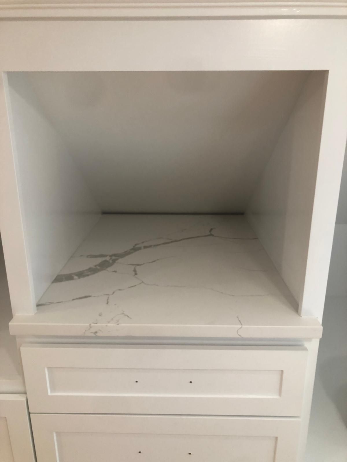 White built-in kitchen cabinet with open niche and marble shelf. Drawer fronts below.