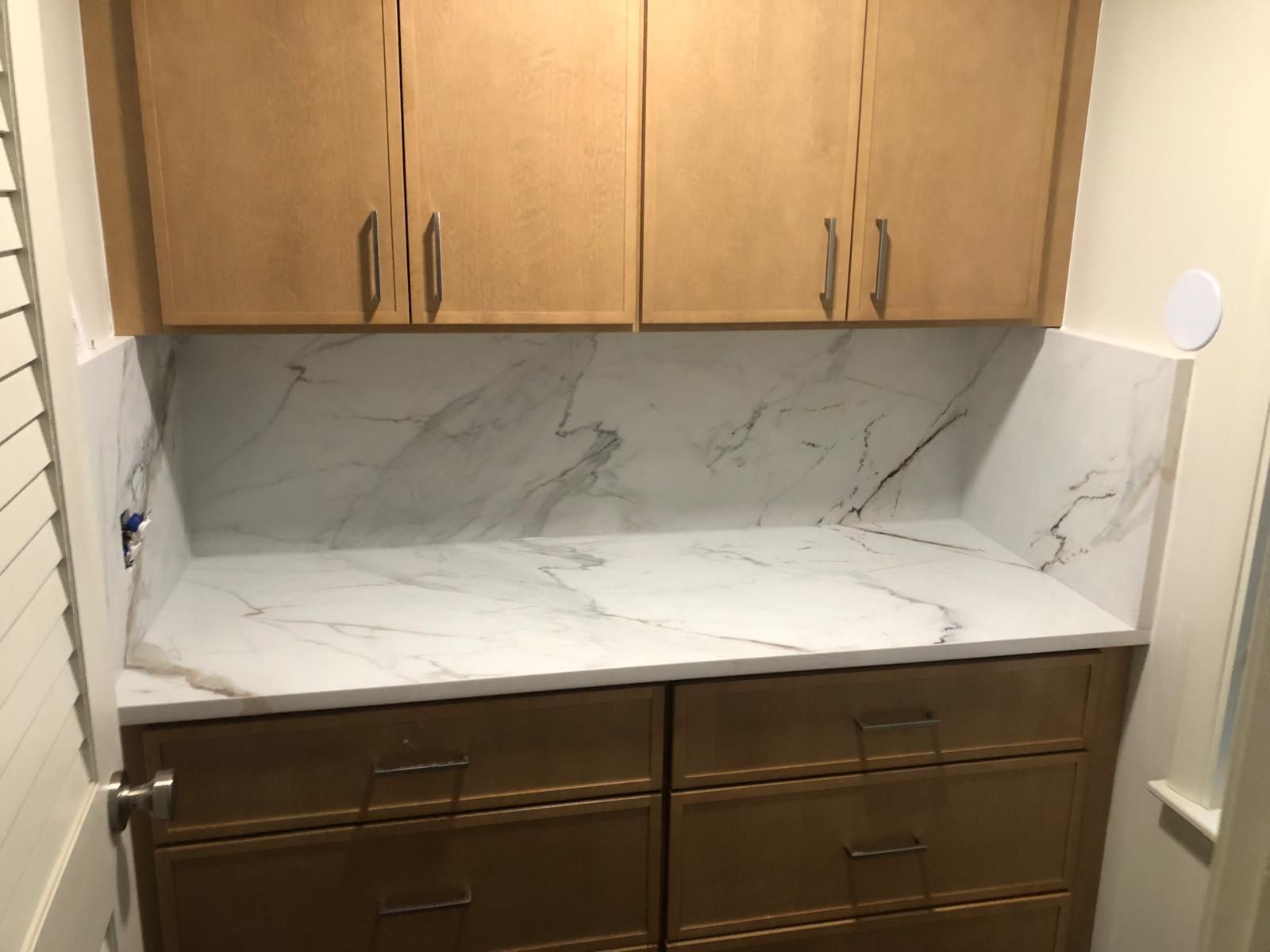 Beige cabinets above a marble-look countertop and drawers.
