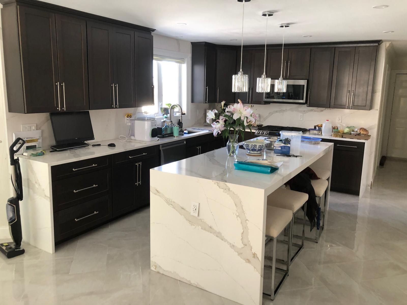 Dark brown kitchen cabinets, white countertops, and an island with bar stools.