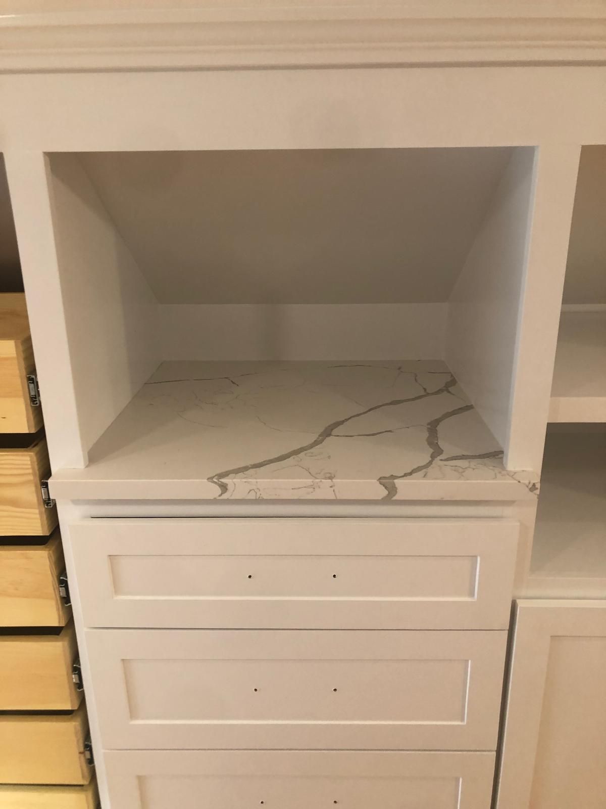White built-in cabinet with quartz countertop and drawers below an open shelf.