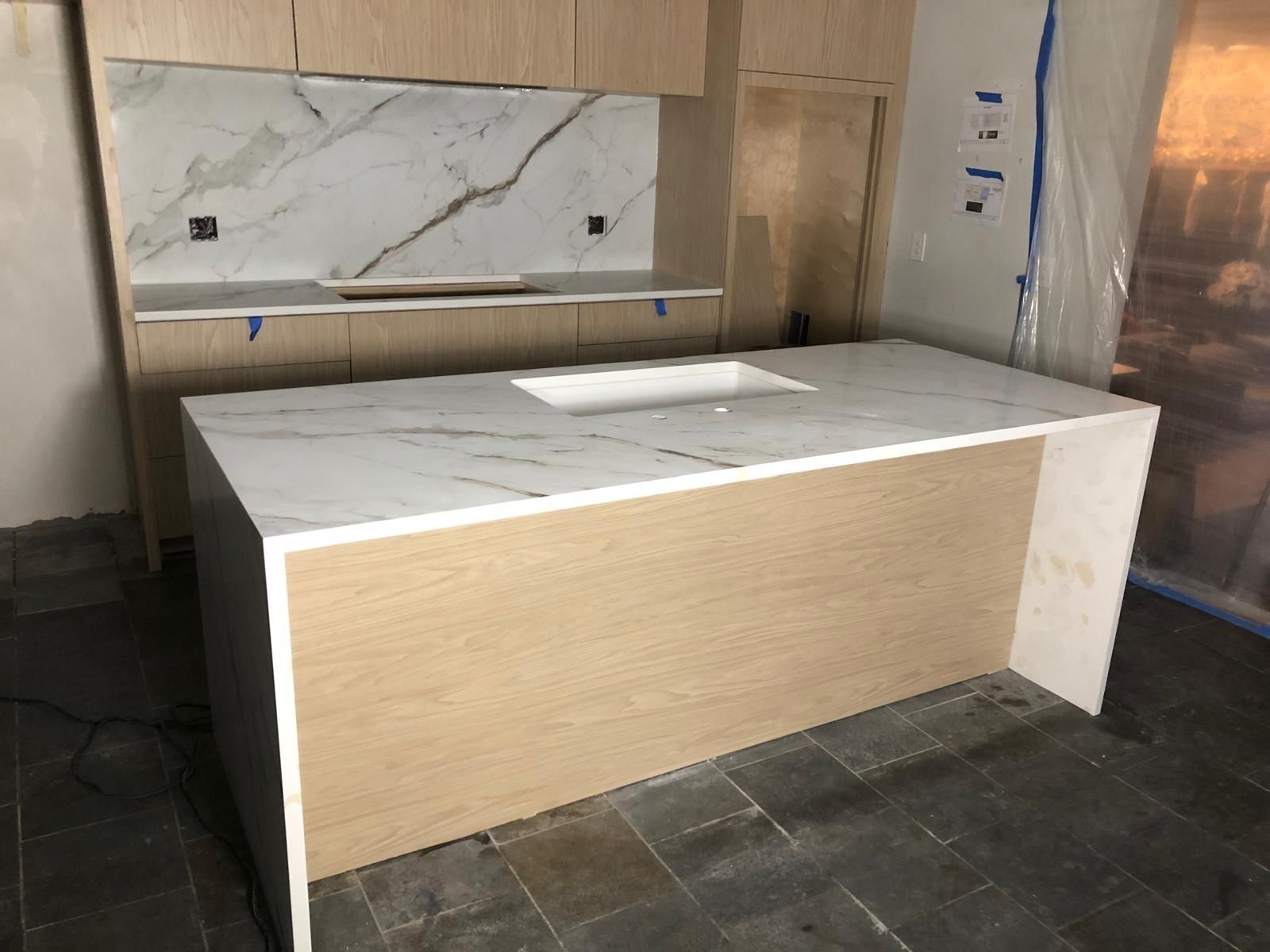 New kitchen with light wood cabinets, white marble countertops, and a large island.