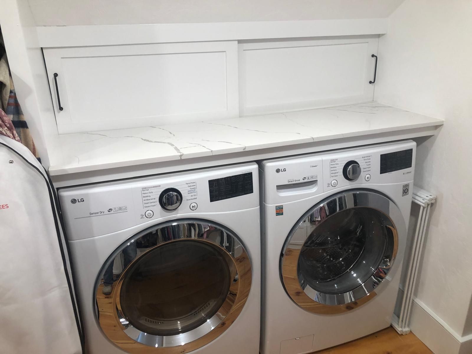 White LG washer and dryer pair with countertop and cabinet in a laundry room.