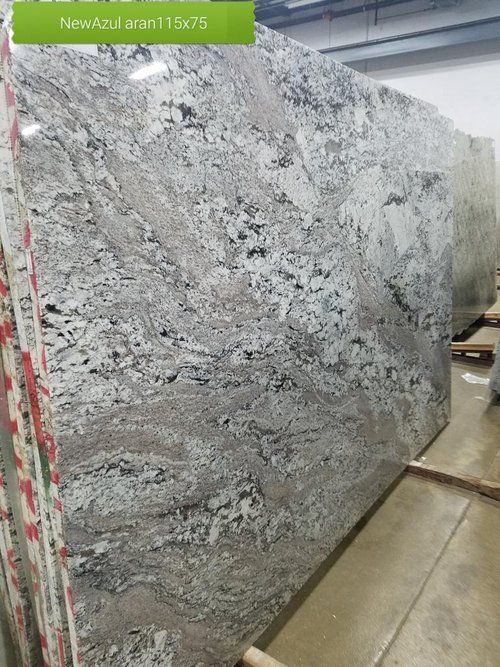 A large granite slab is sitting on a wooden pallet in a warehouse.