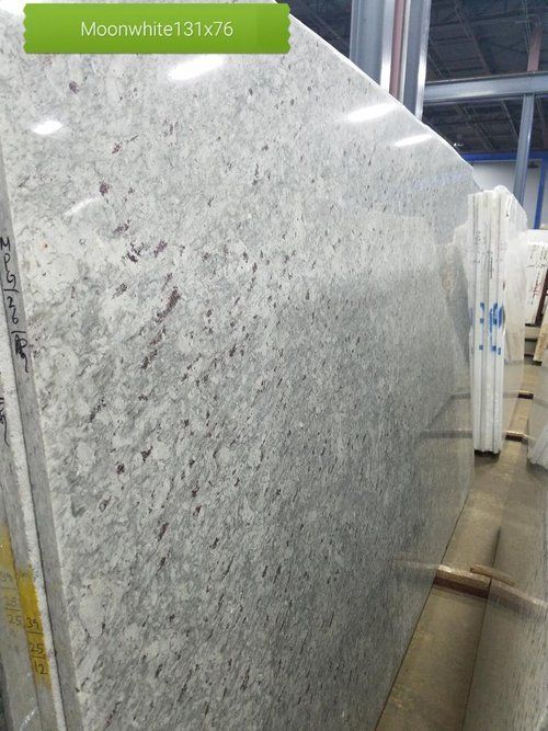 A large white granite slab is sitting in a warehouse.