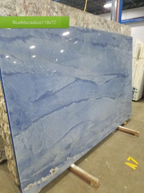 A large blue marble slab is sitting on wooden pallets in a warehouse.