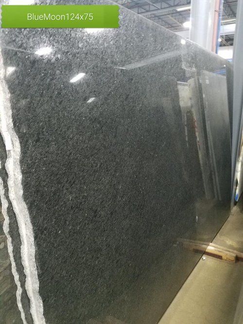 A large black granite slab is sitting on top of a table in a warehouse.