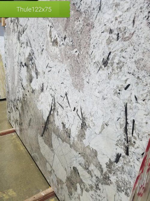 A large white granite slab is sitting on top of a wooden shelf.
