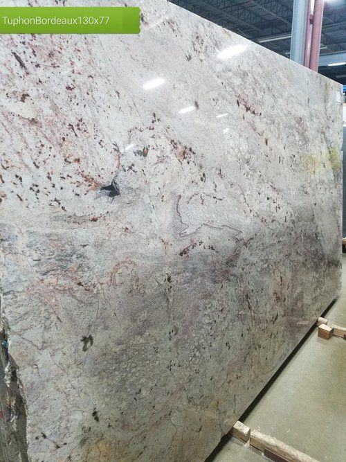 A large slab of granite is sitting on a shelf in a warehouse.