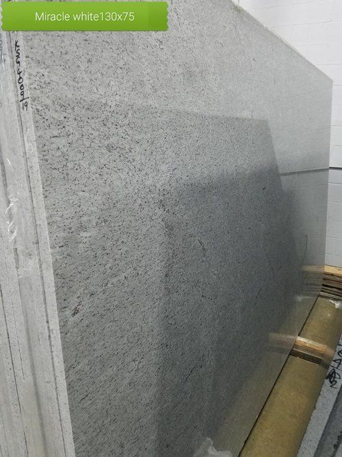 A large white granite slab is sitting on top of a wooden table.