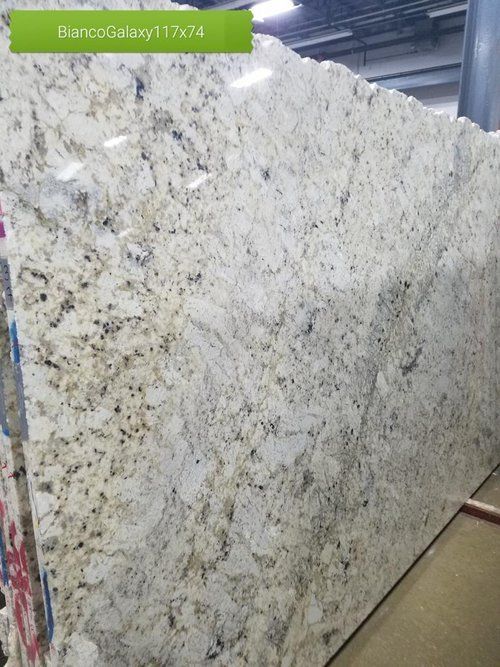 A large white granite slab is sitting in a warehouse.
