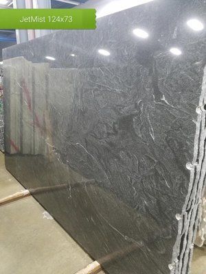 A large black granite slab is sitting on top of a concrete floor in a warehouse.