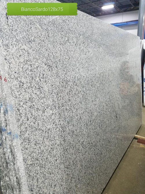 A large white granite slab is sitting on the floor in a warehouse.