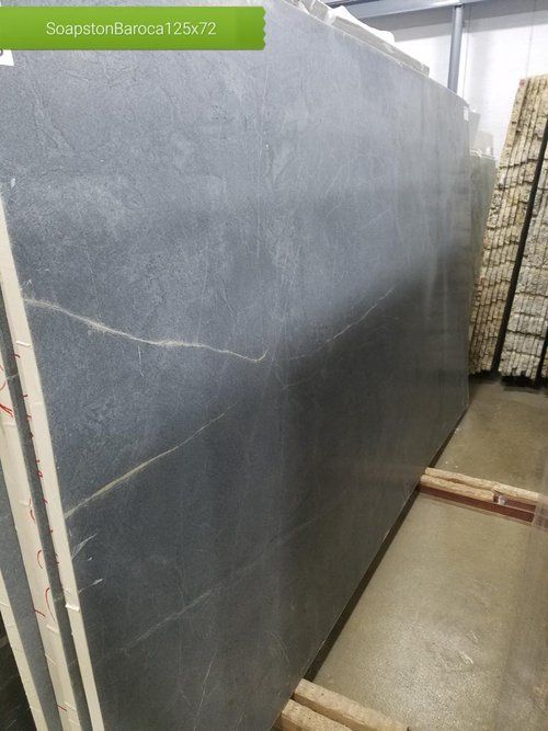 A large slab of soapstone is sitting on a wooden rack in a warehouse.