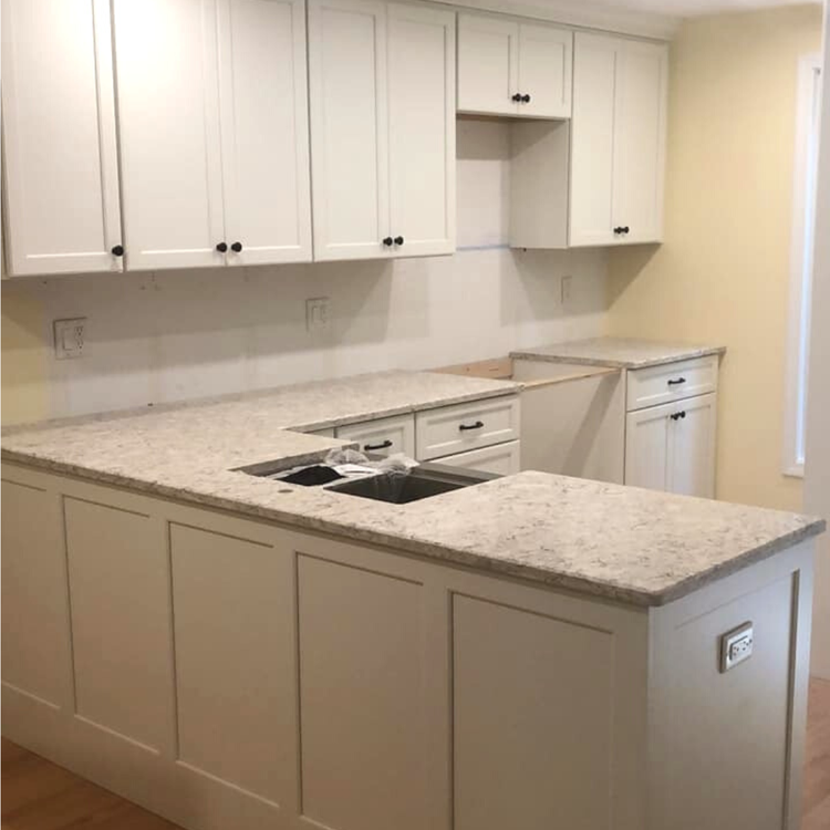 White modern kitchen with stainless steel appliances, and wood flooring.