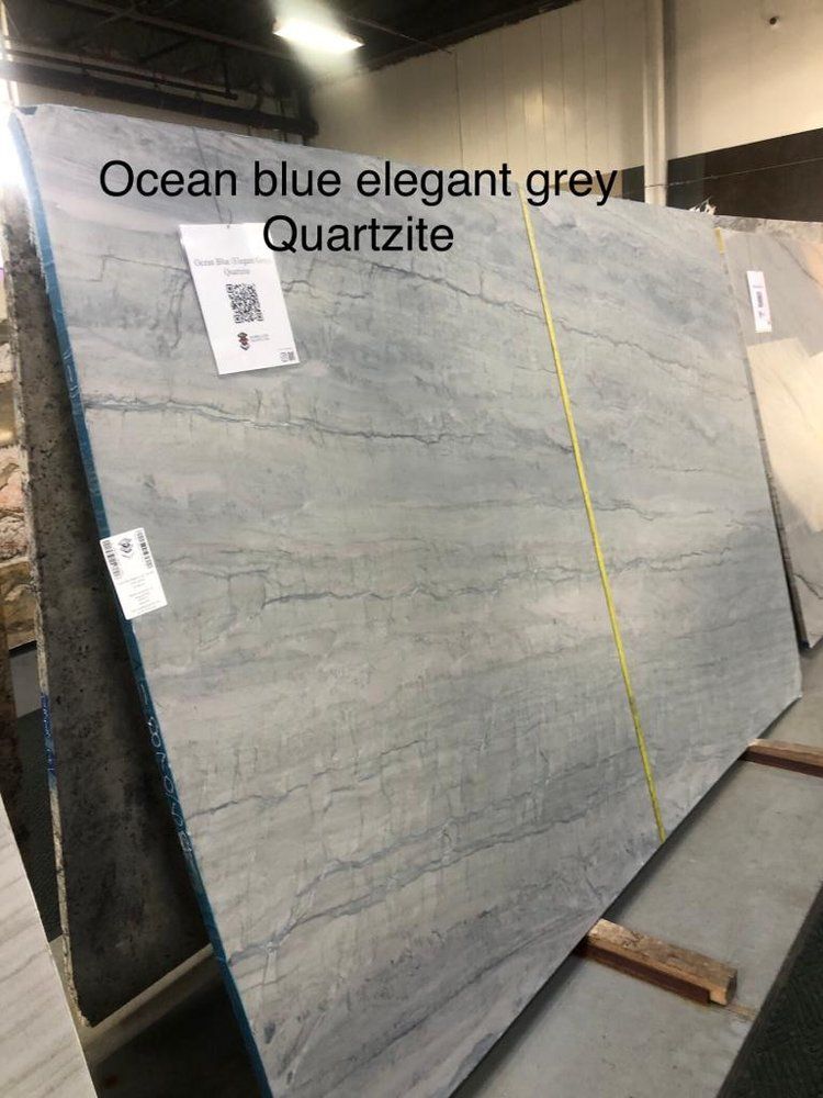 A large slab of ocean blue elegant grey quartzite is sitting on top of a wooden pallet.