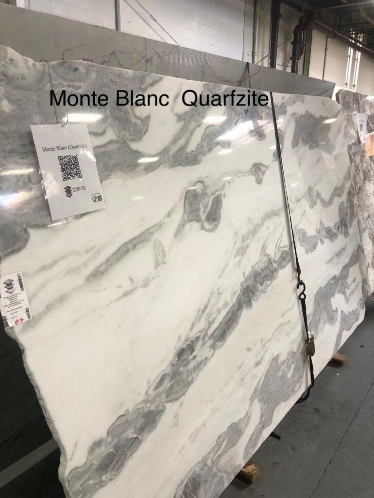 A large white and gray marble slab is sitting in a warehouse.