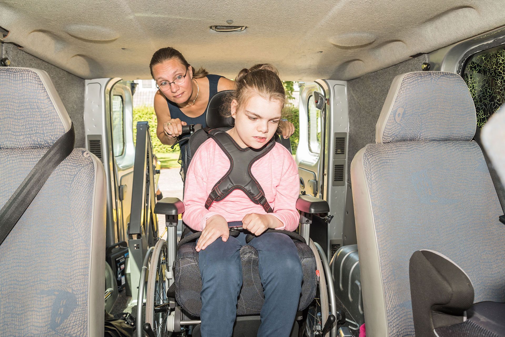 disabled child in a wheelchair being cared for by a special needs carer