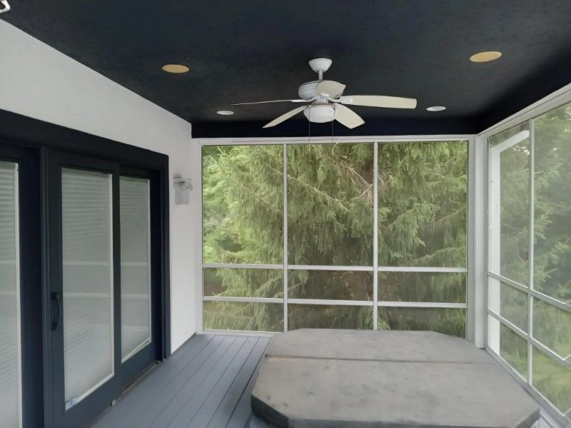 A screened in porch with a ceiling fan