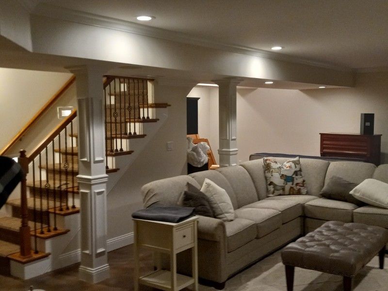 A living room with a sectional couch and stairs
