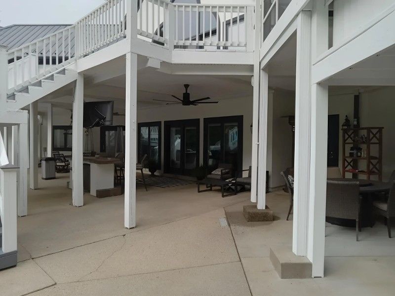 A large patio with a white railing and a ceiling fan.