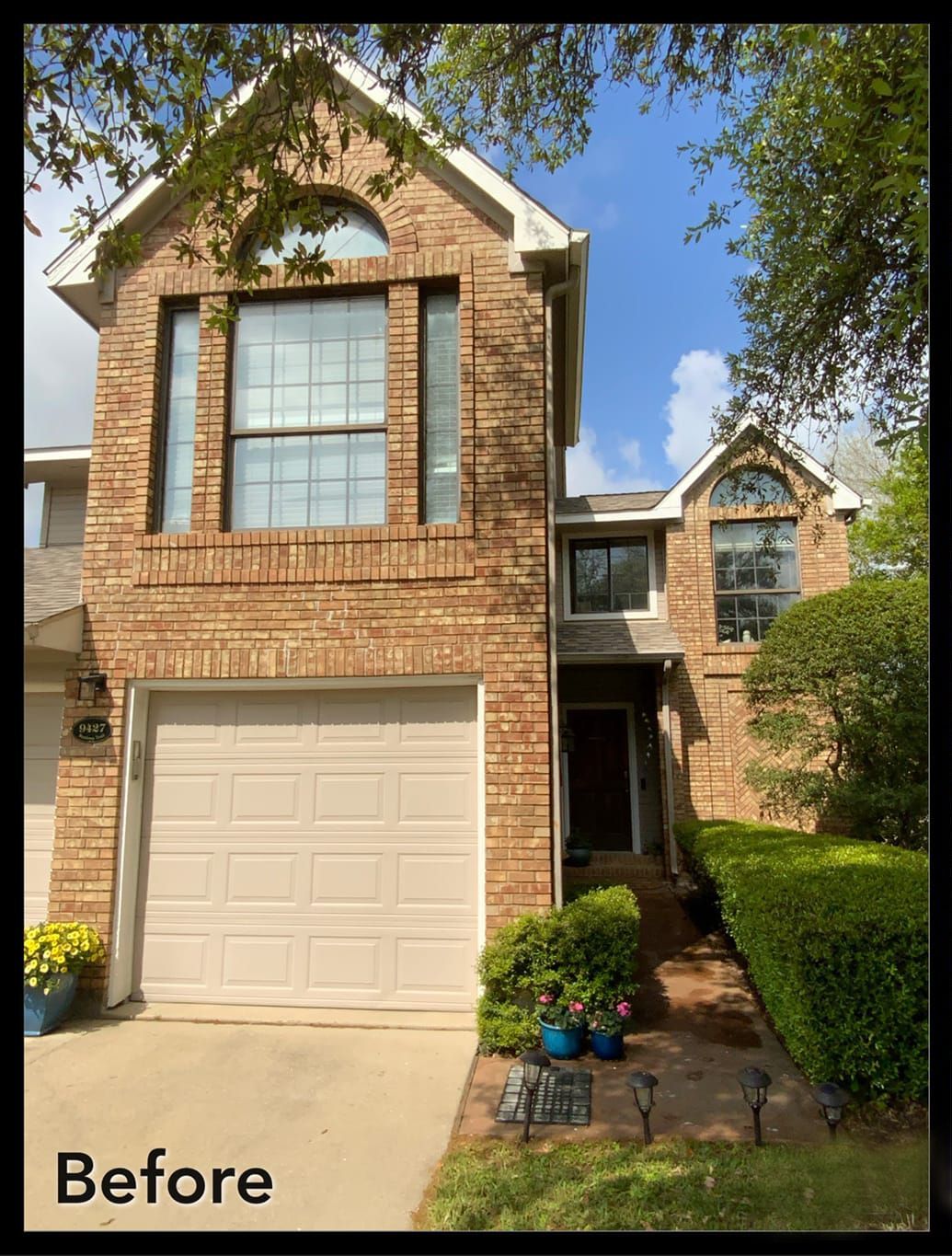 A before picture of a brick house with a white garage door