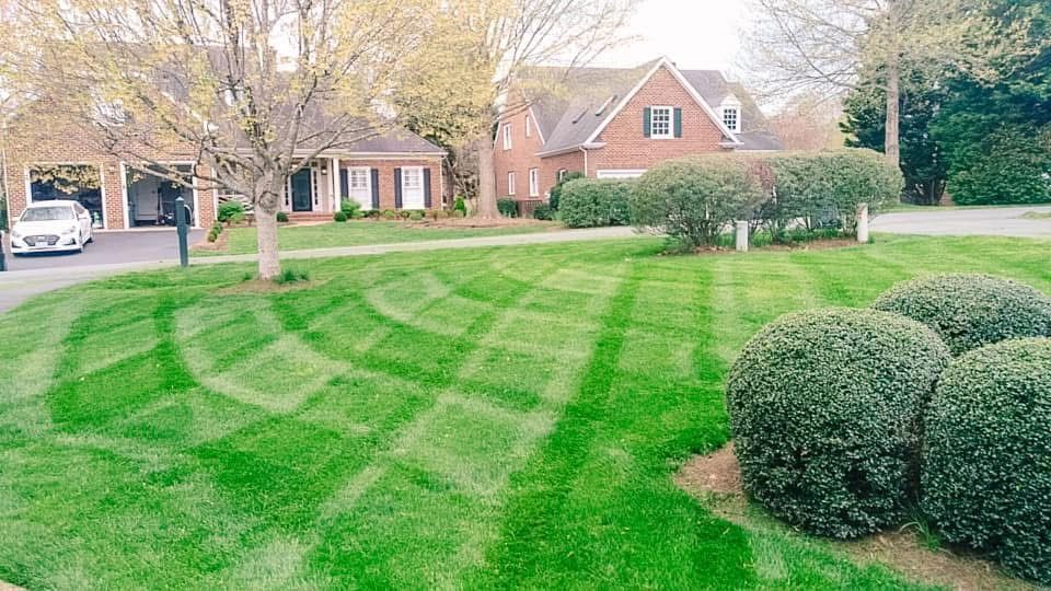 Lawn of a home with a geometric mowing pattern, a brick house, and garage in the background.