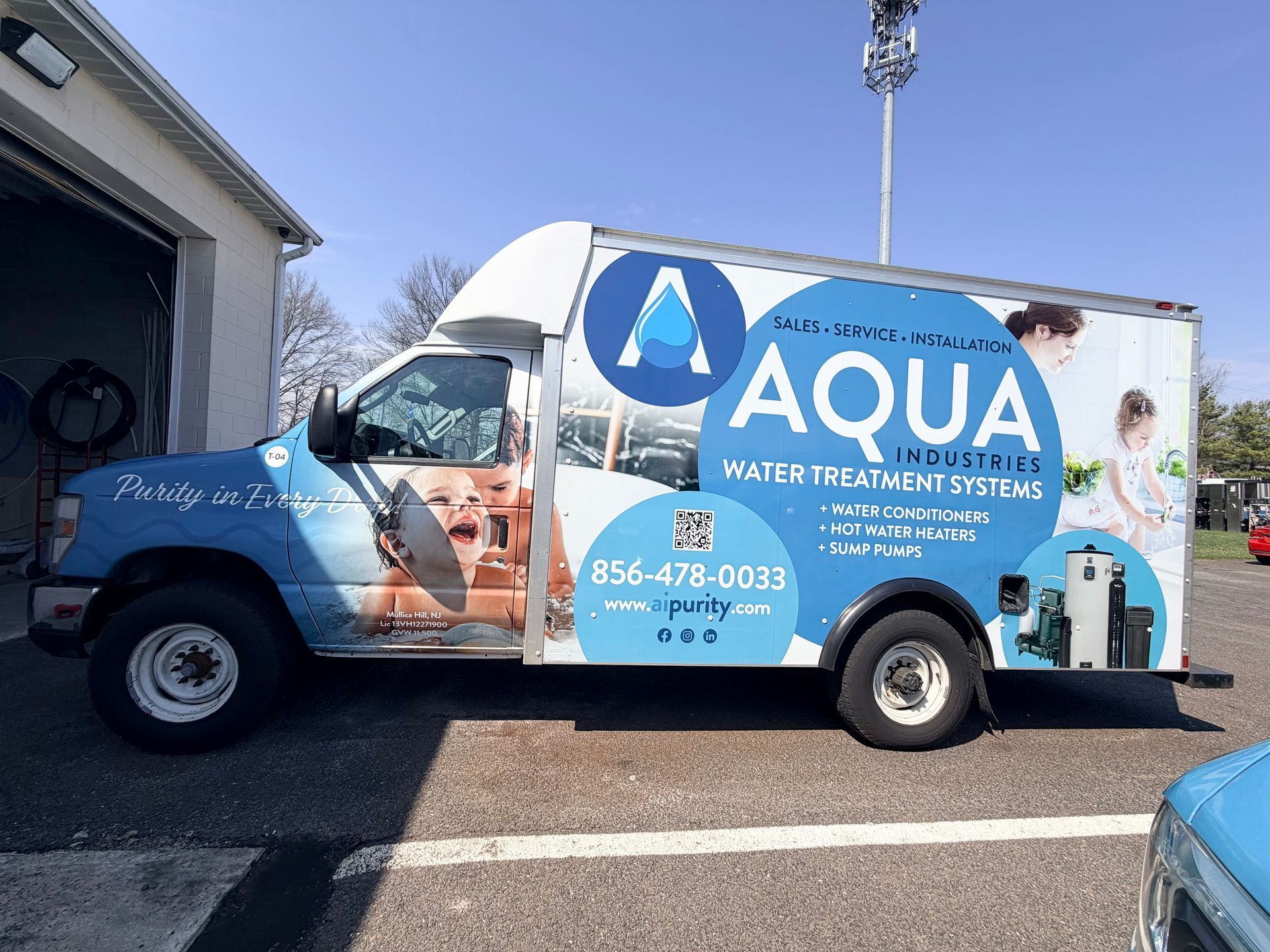 A blue and white Aqua water treatment service truck parked outdoors on a sunny day.