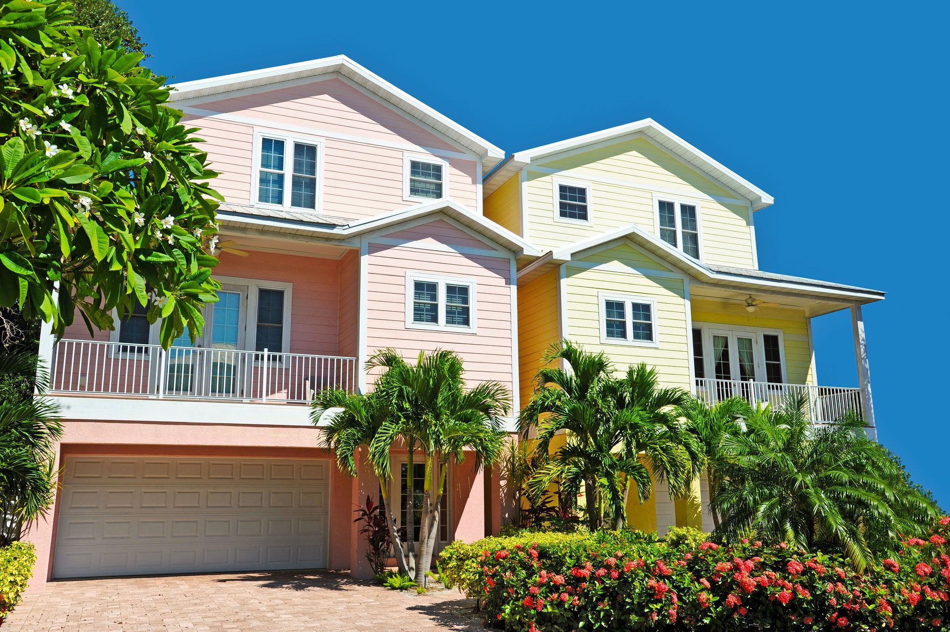 A pink and yellow house with a garage and a blue sky in the background.