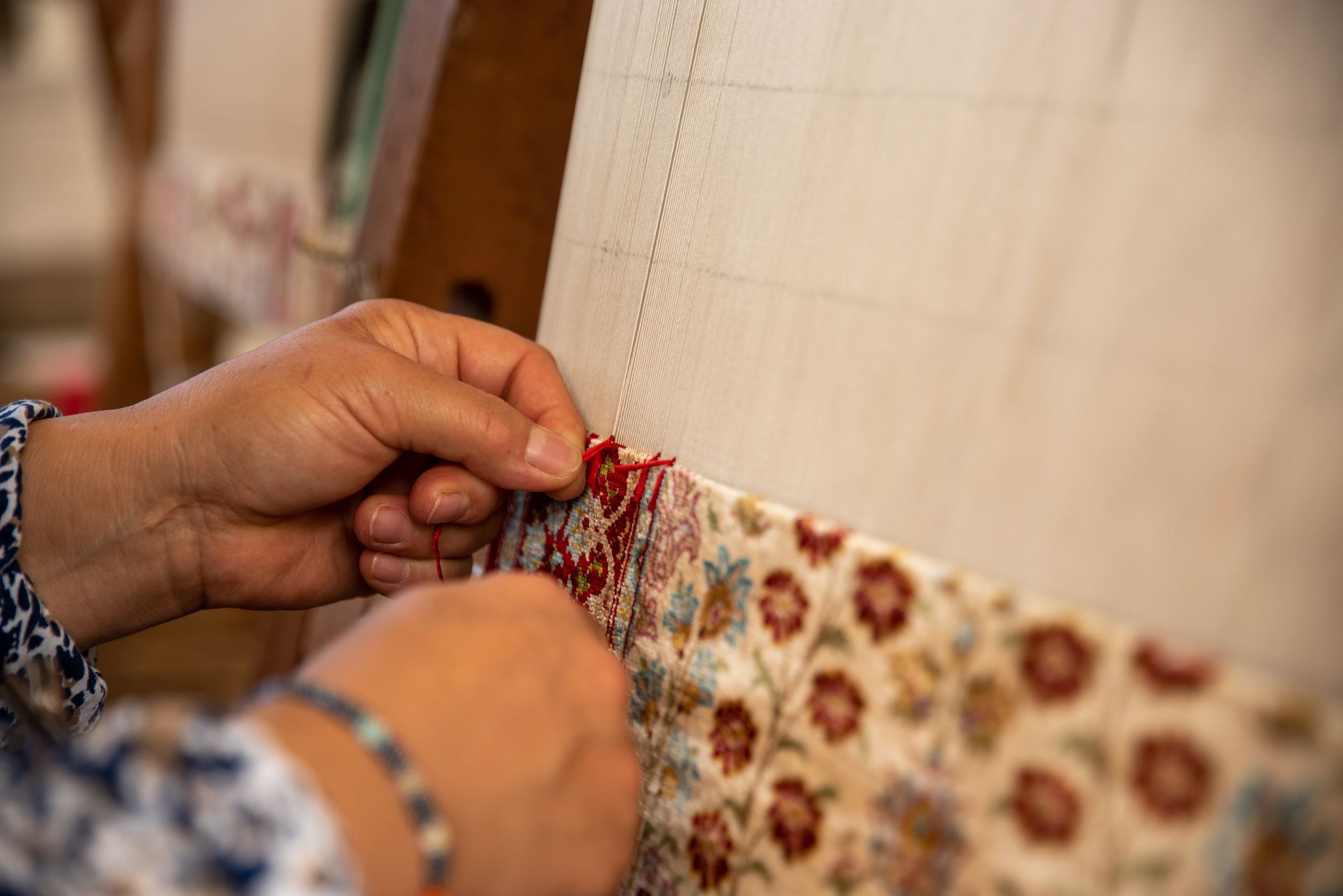Hands weaving a colorful patterned fabric on a loom, close-up.