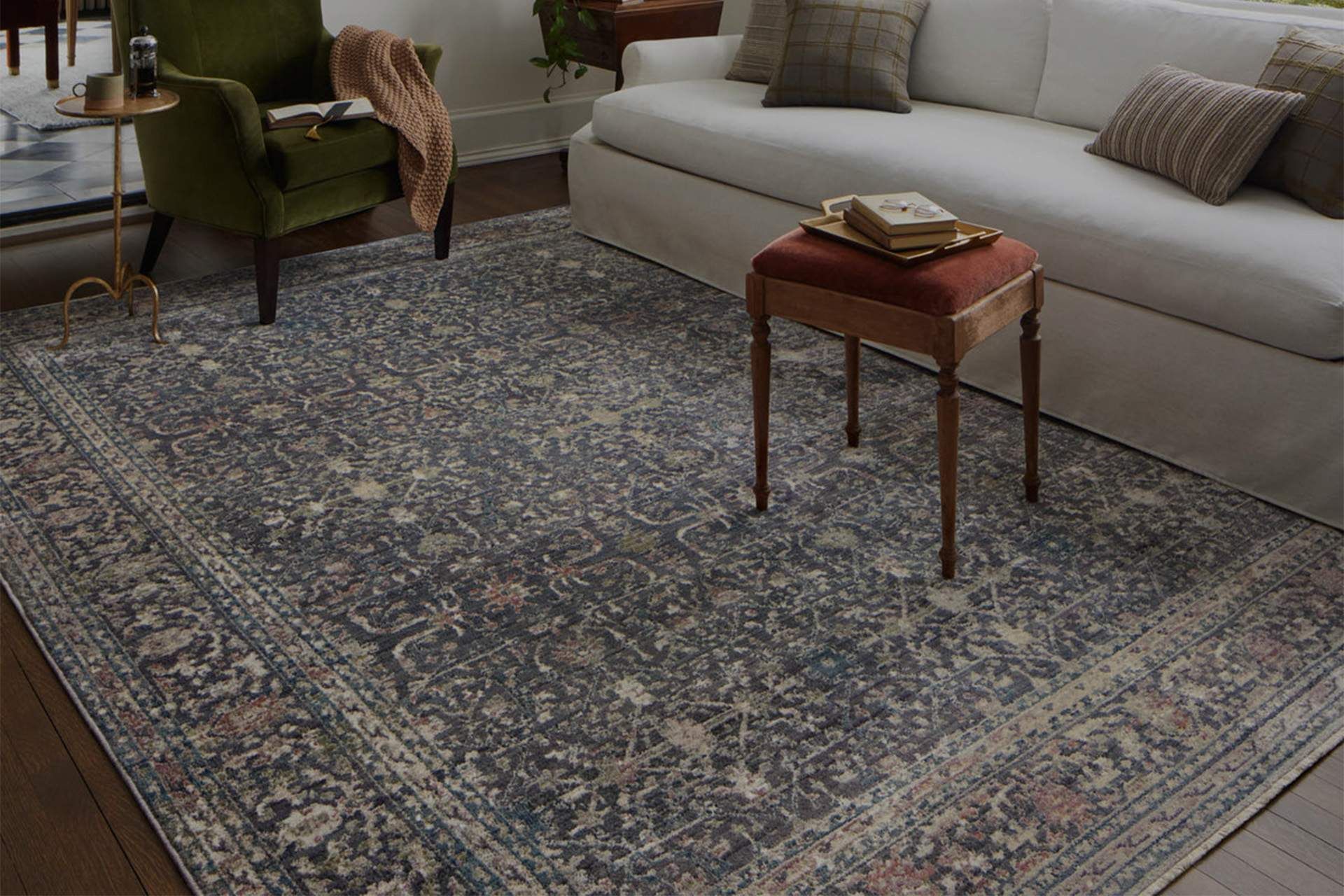 Patterned rug in a cozy living room with a sofa, green chair, and small wooden side table.
