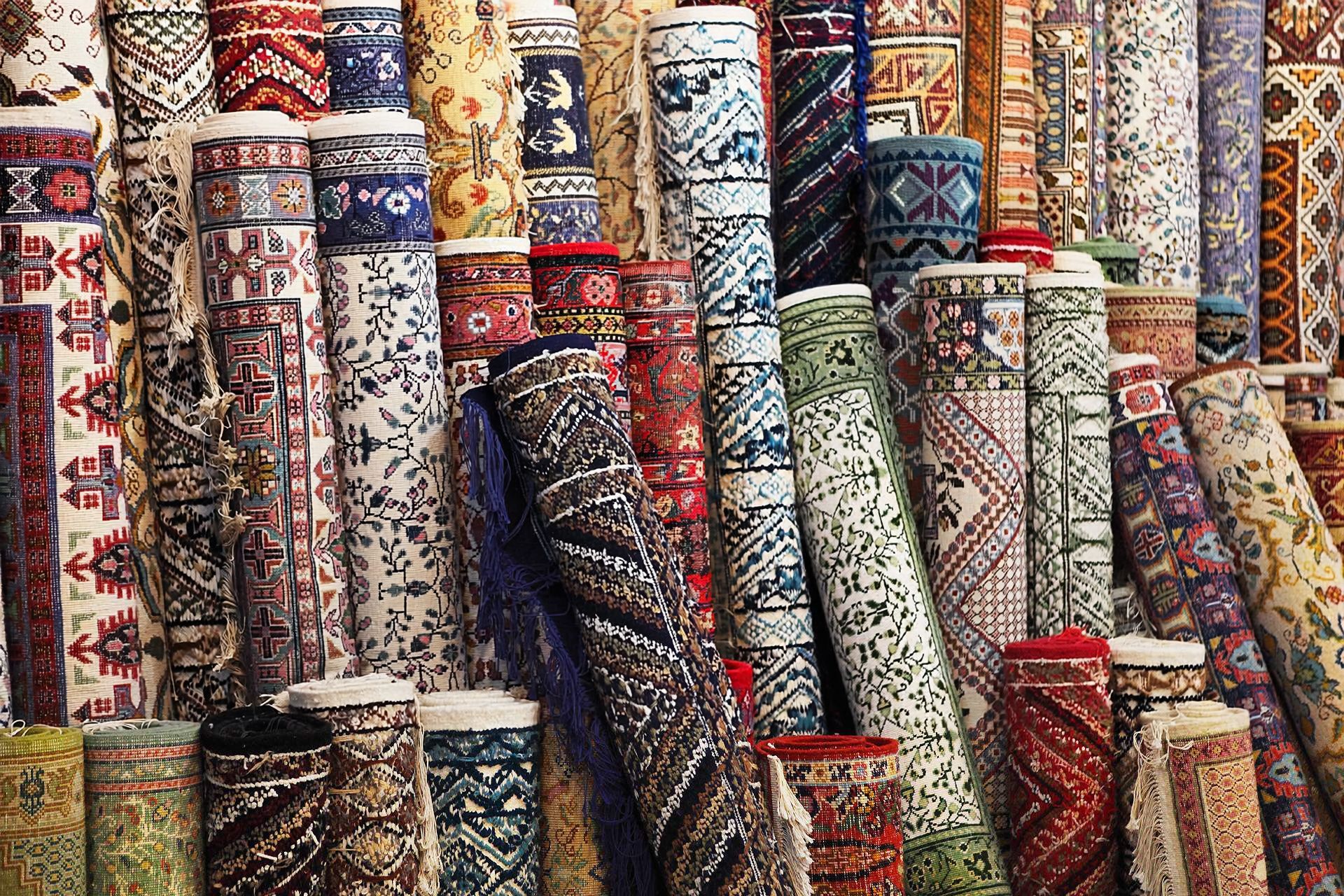 Stacked colorful patterned rugs in a textile market stall