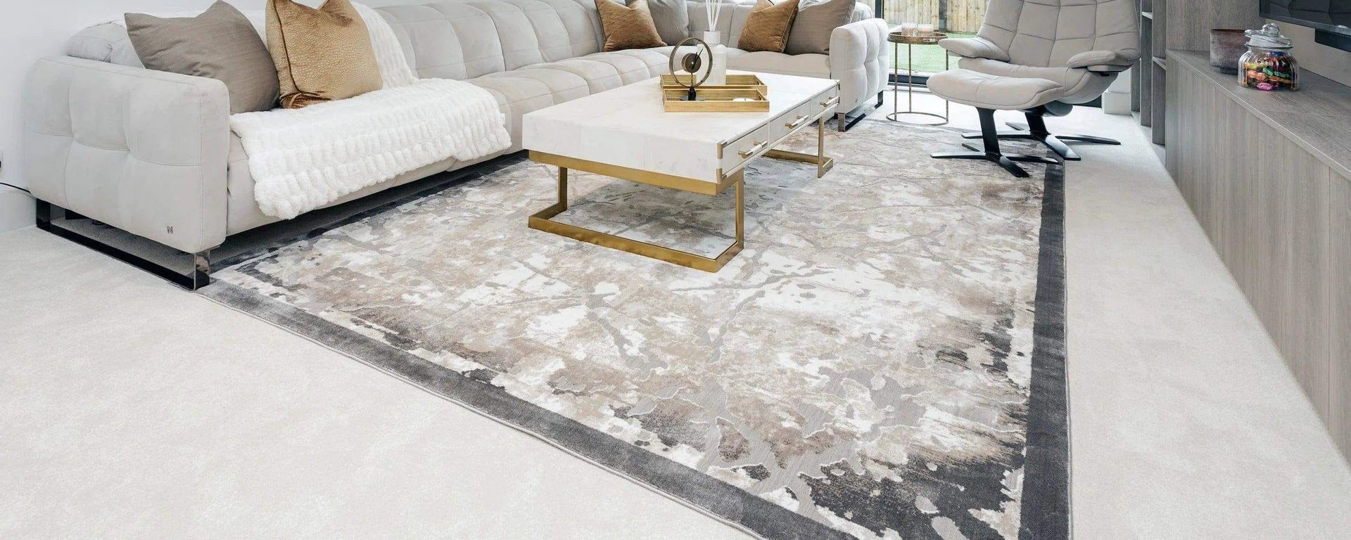Modern living room with light sectional sofa, gold coffee table, and gray patterned rug