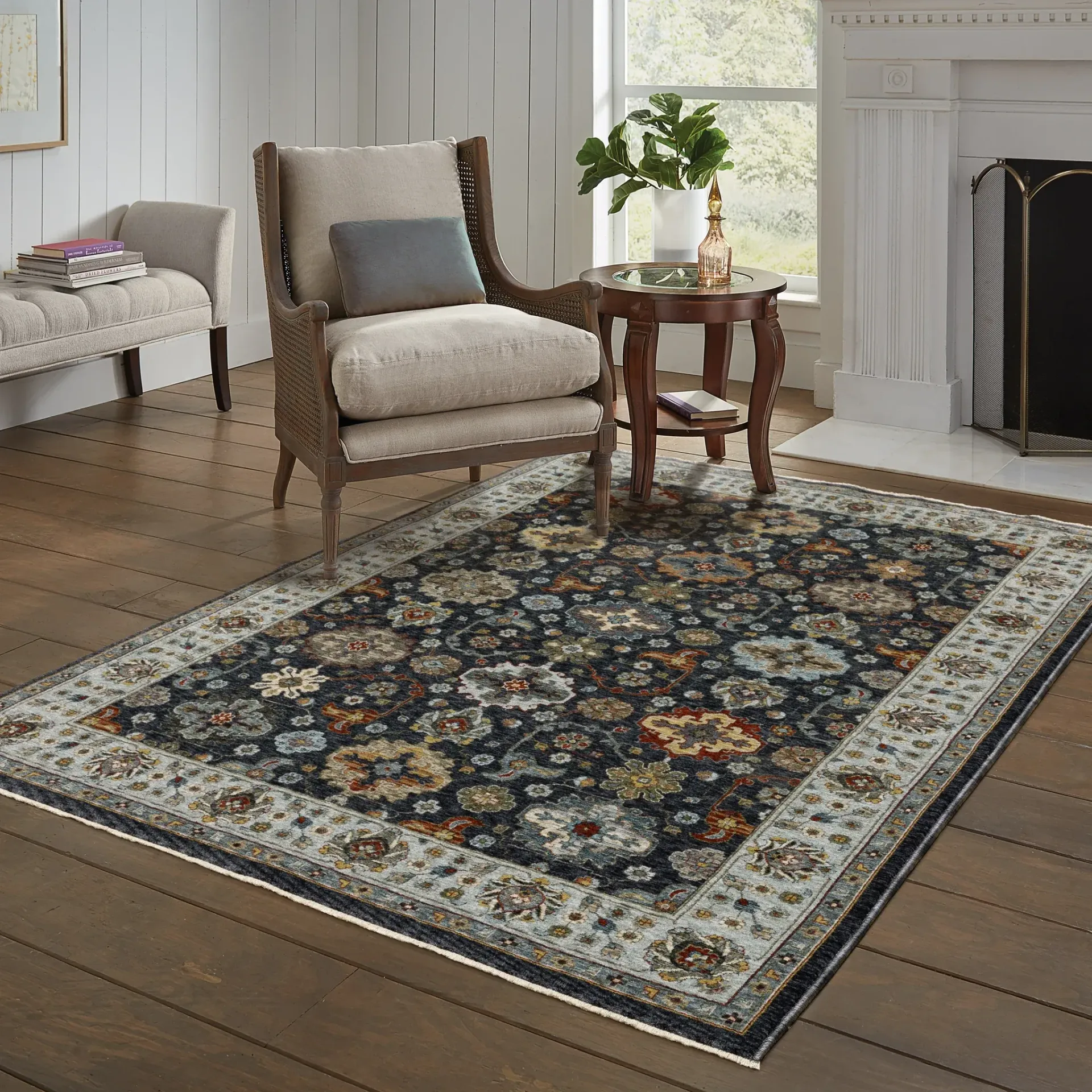 Traditional patterned rug in a bright living room with chairs, side table, plant, and fireplace.