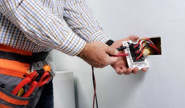 An electrician is installing a light switch on a wall.