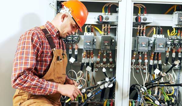 An electrician is working on an electrical panel.
