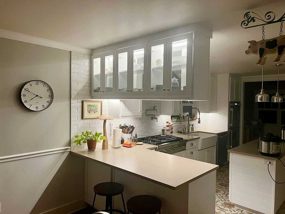A kitchen with a clock on the wall and a stove top oven.