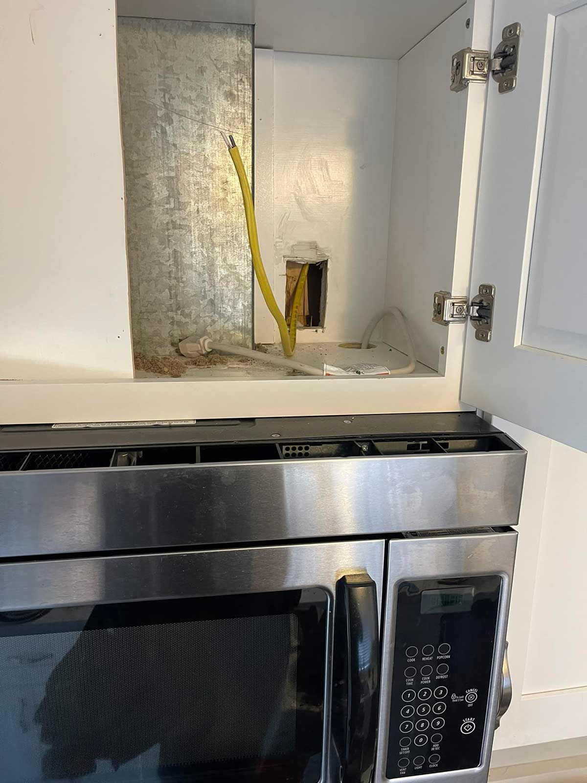 A stainless steel microwave is sitting inside of a cabinet