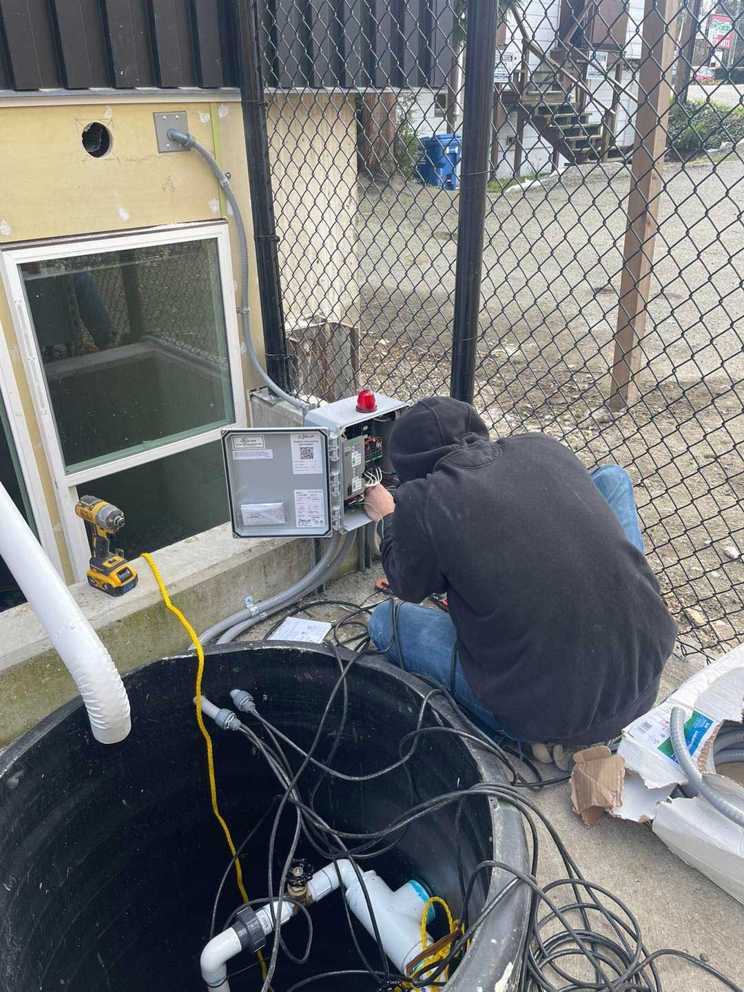 A man is working on a septic tank outside of a house.