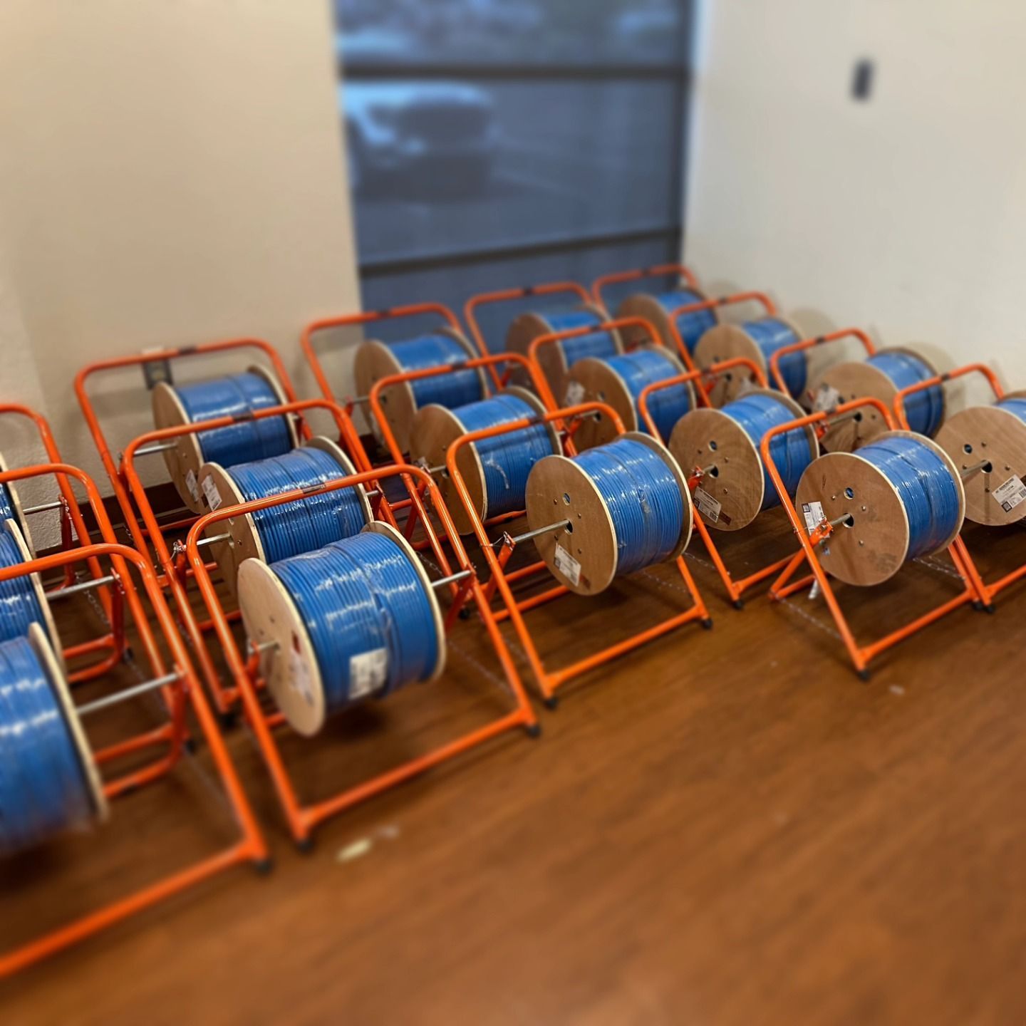 Rows of blue cable spools on orange stands in a room with a window.