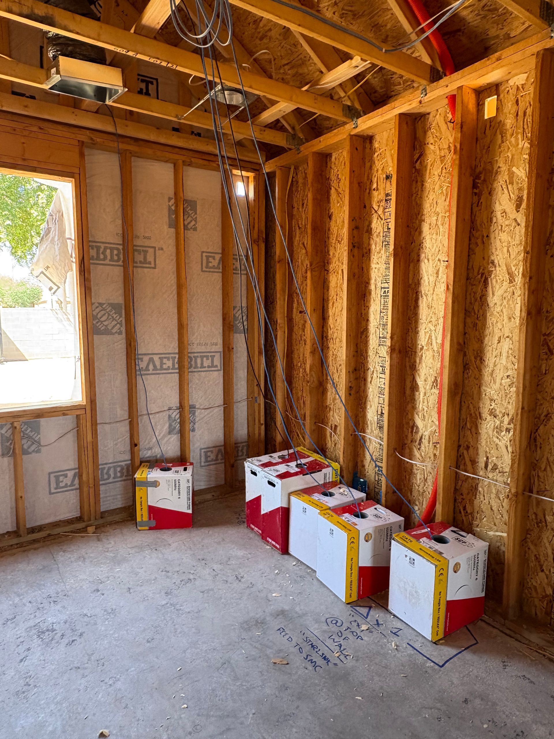 Interior of a building under construction, wooden framing, concrete floor, boxes with red and yellow accents.