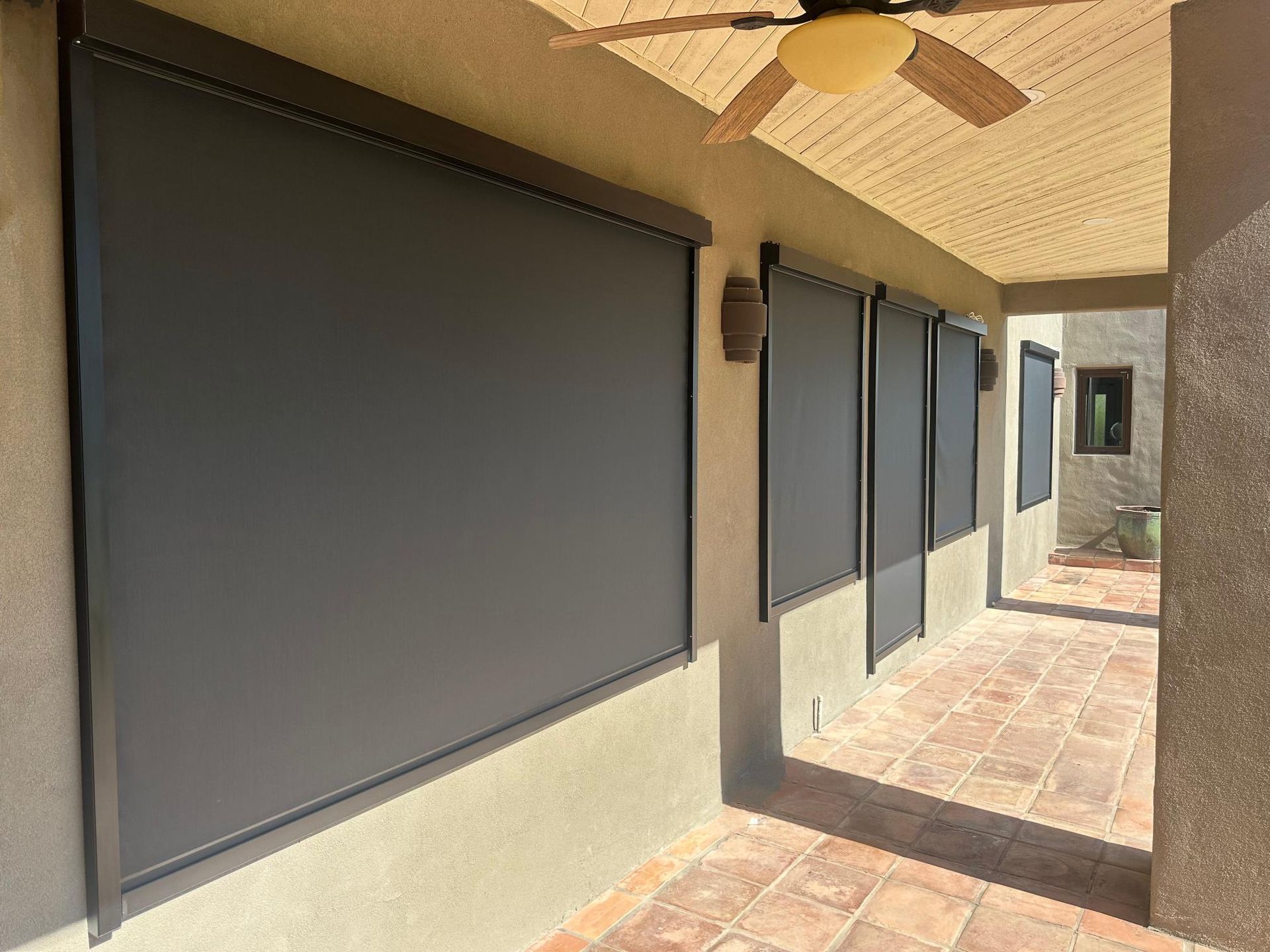 Outdoor patio with several black sun shades pulled down.