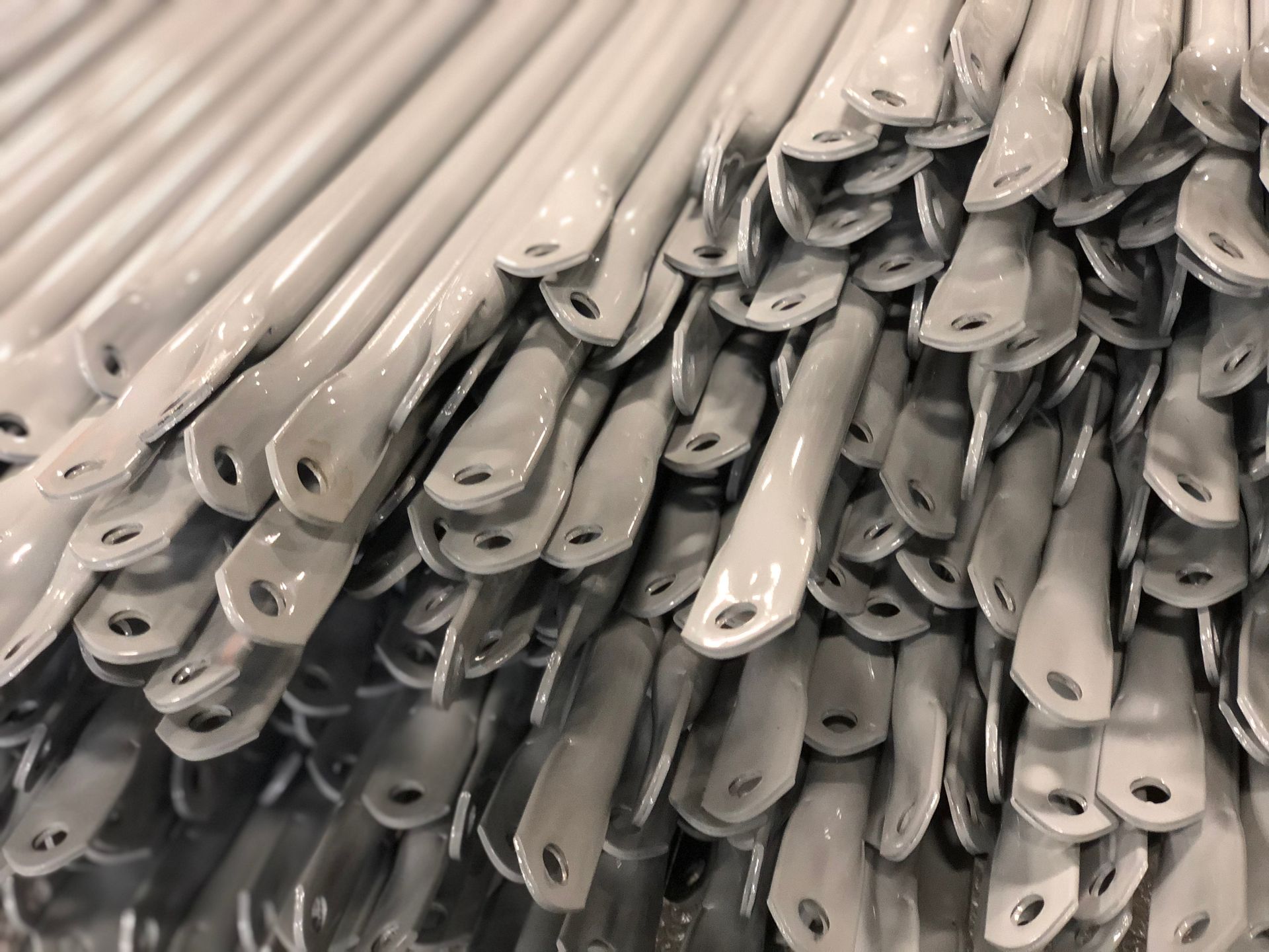 Stacked white plastic hangers with metal hooks, tightly bundled together