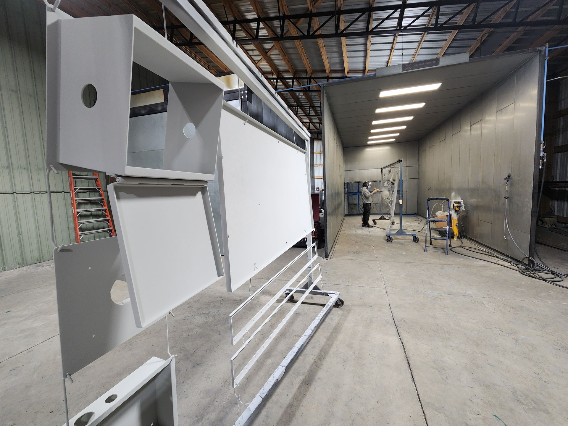 Industrial workshop with large metal panels and ducts in a warehouse-like space under construction