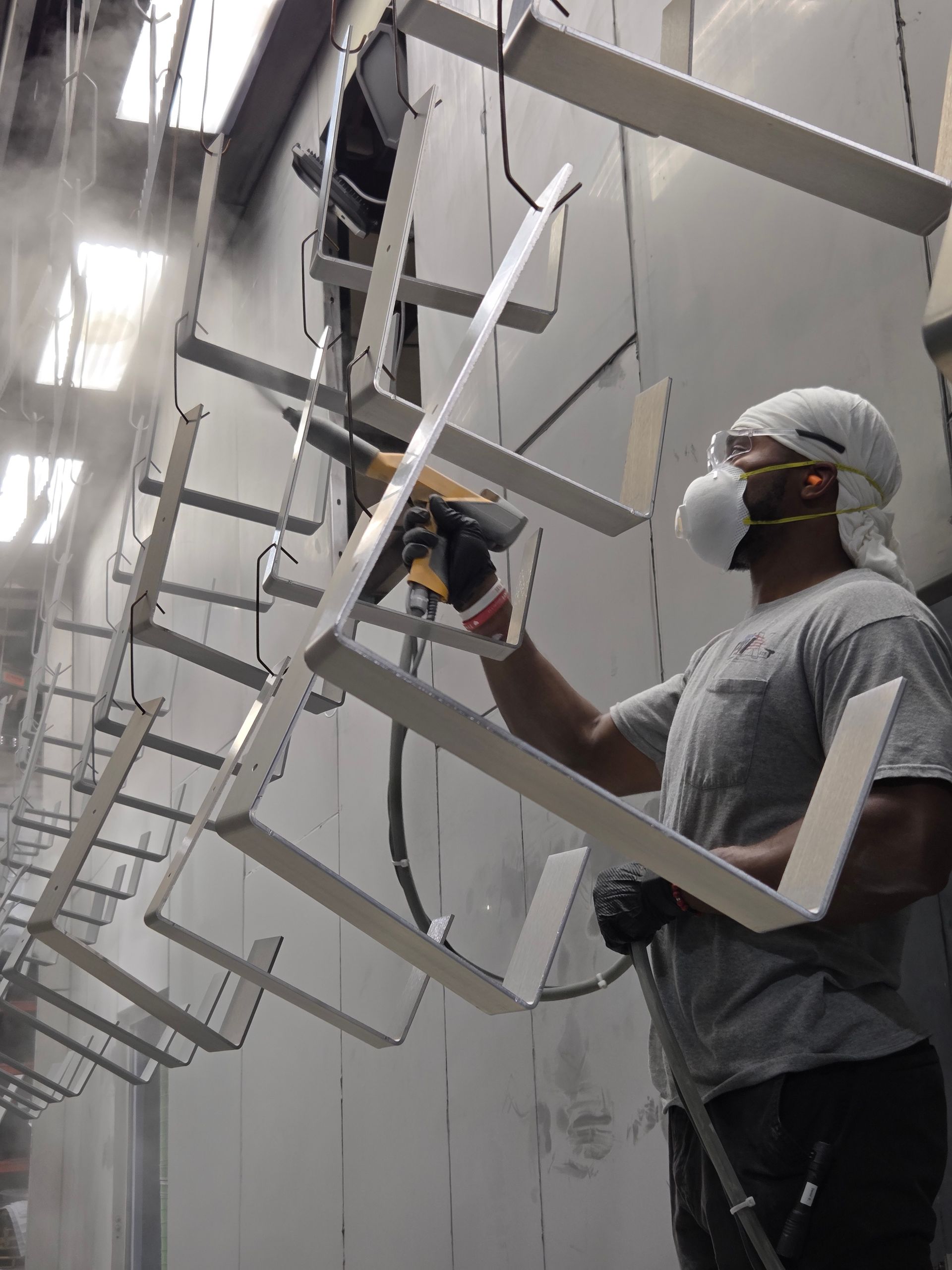 Worker spray-painting large metal letters in an industrial workshop