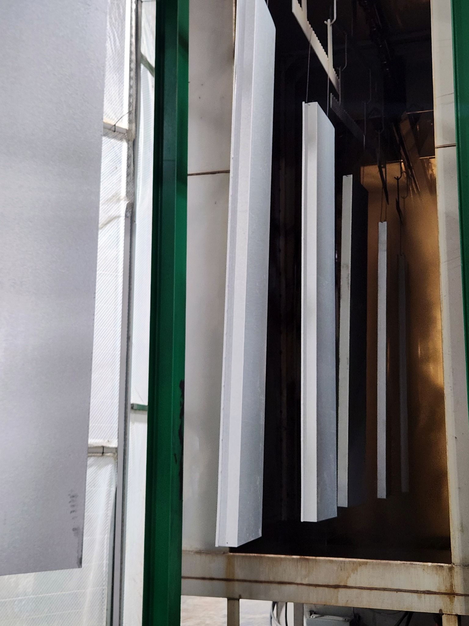 Row of white hanging strips in a narrow industrial corridor with dark walls and metal framing